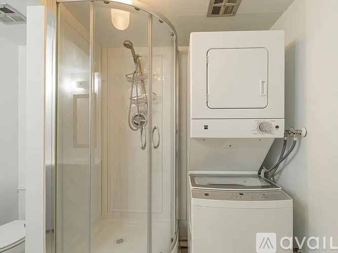 A white bathroom with a shower and a washer and dryer.