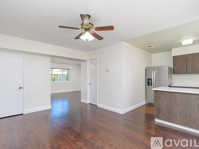A spacious room with a ceiling fan and wooden flooring.