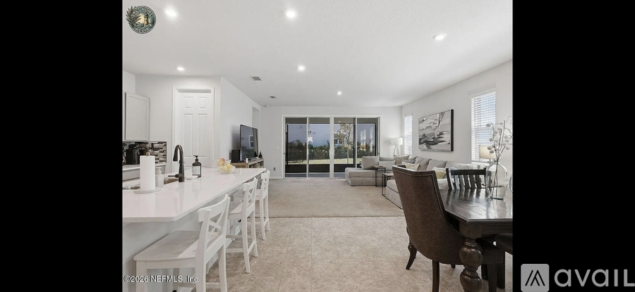 A modern kitchen with white cabinets and a dining area with a table set for two.