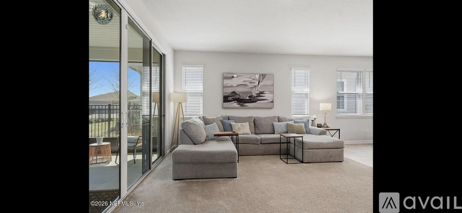 A living room with a grey sofa and a large painting on the wall.