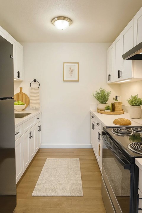 A kitchen with a black fridge and stove top oven.