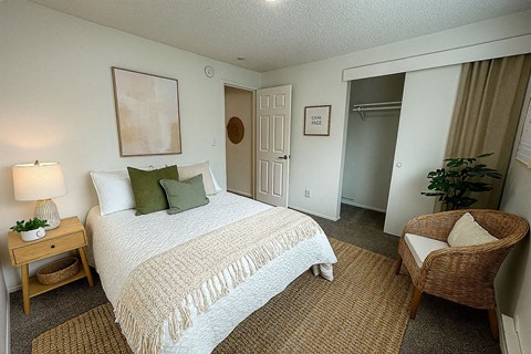 A bedroom with a bed, chair, and painting on the wall.