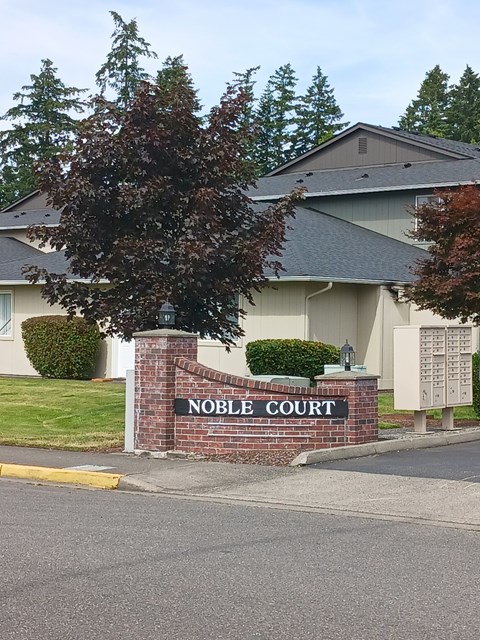 A sign that says Noble Court stands in front of a building.