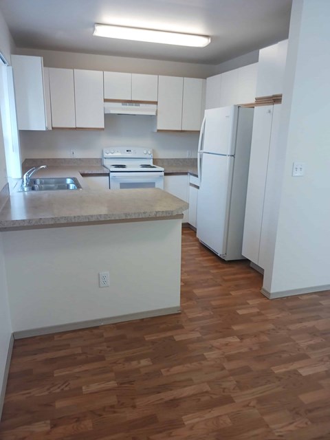 A kitchen with white cabinets and a wooden floor.