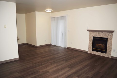 A living room with a fireplace and wood flooring.