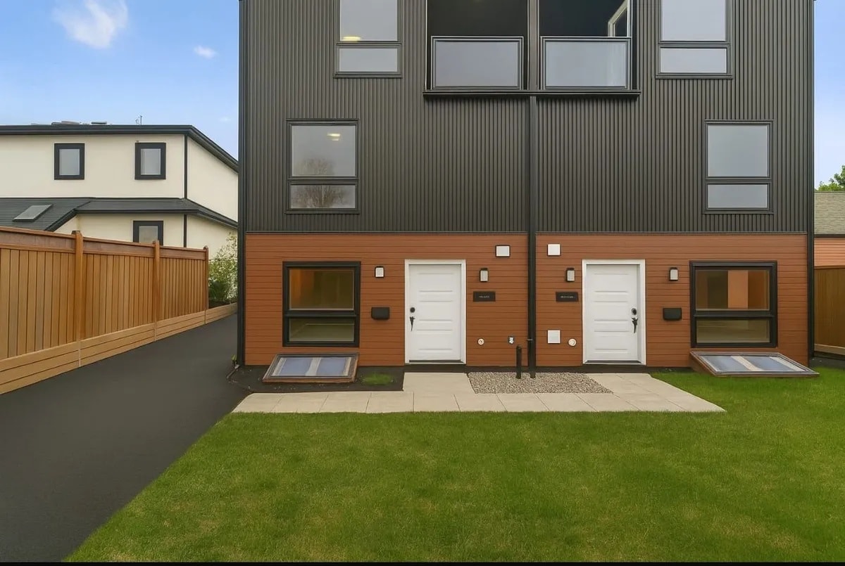 A modern house with a grey facade and white doors.