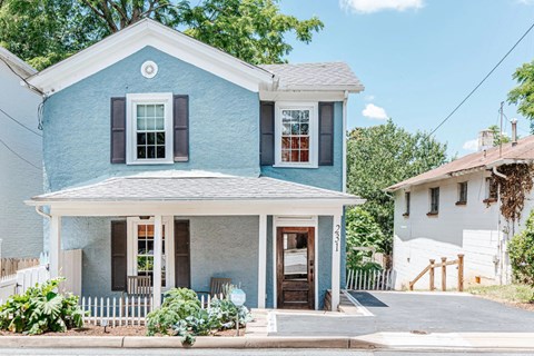 A blue house with a white porch and a white fence.