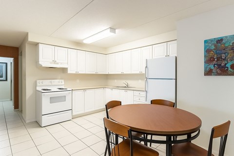 A kitchen with a table and chairs and a refrigerator.