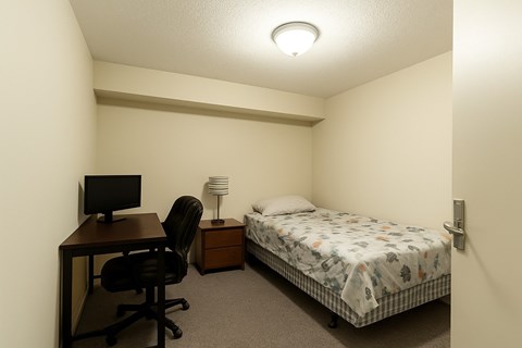 A small bedroom with a bed, desk, and chair.