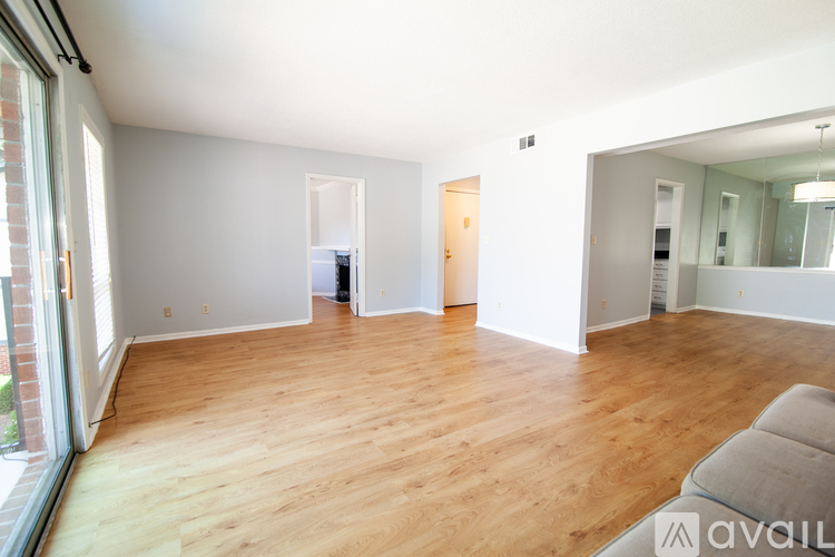 A spacious room with wooden flooring and white walls.