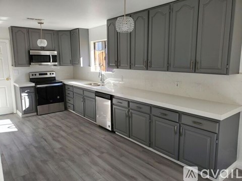 A kitchen with dark grey cabinets and a white countertop.