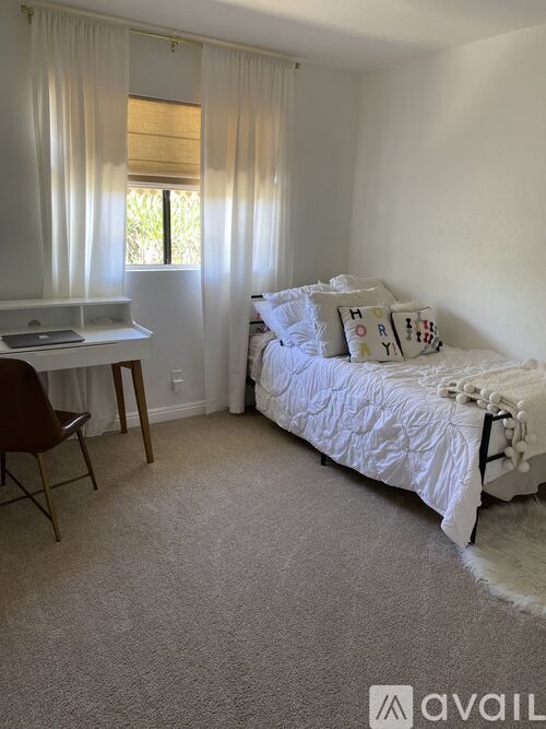 A bedroom with a bed, desk, and chair.