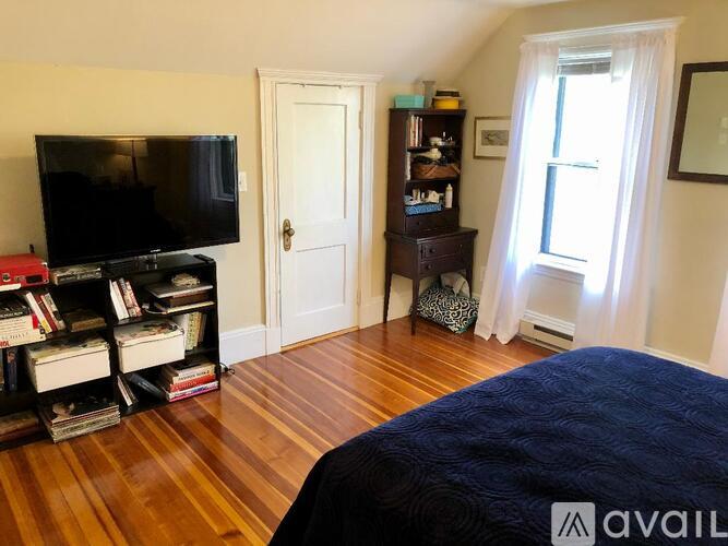 A bedroom with a bed, a television, a bookshelf, and a window.