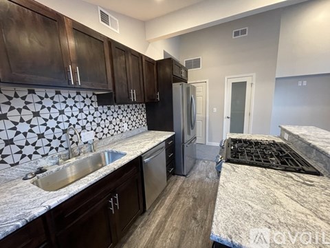 A kitchen with dark brown cabinets and a black refrigerator.