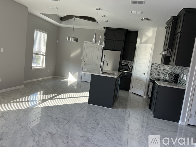 A kitchen with black cabinets and a marble floor.