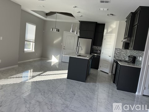A kitchen with black cabinets and a marble floor.