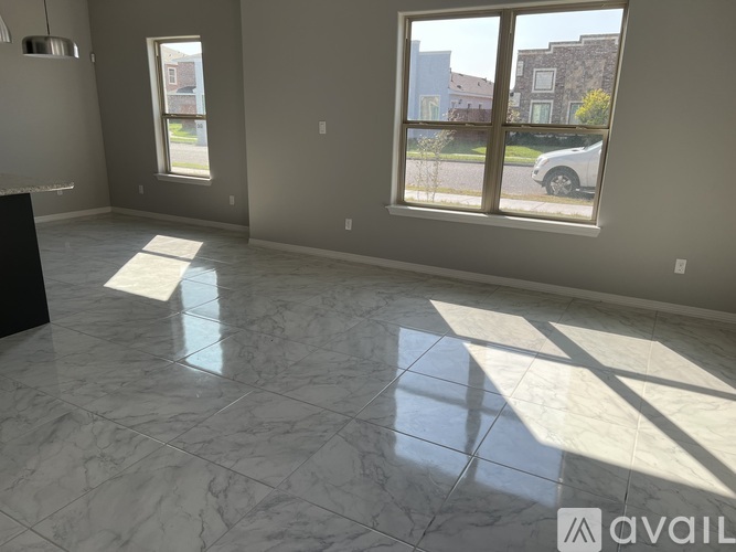 A spacious room with marble flooring and large windows.