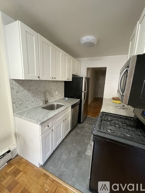 A kitchen with white cabinets and a black fridge.