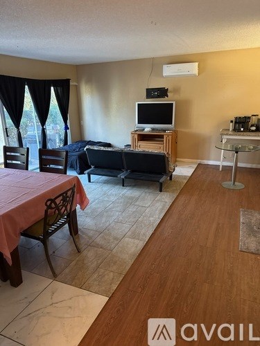 A living room with a television, a couch, and a dining table.