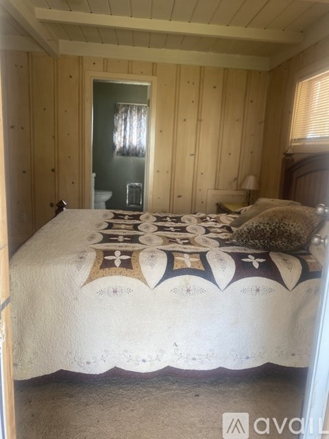 A bedroom with a bed covered in a white and patterned bedspread.