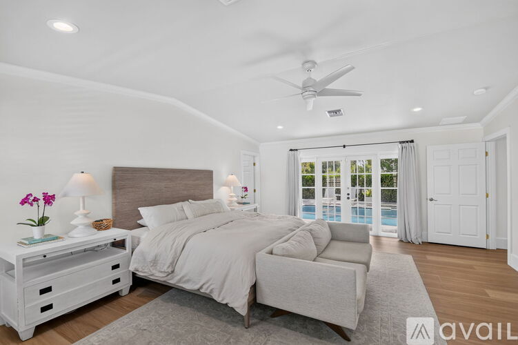 A bedroom with a large bed and a view of a pool through the window.