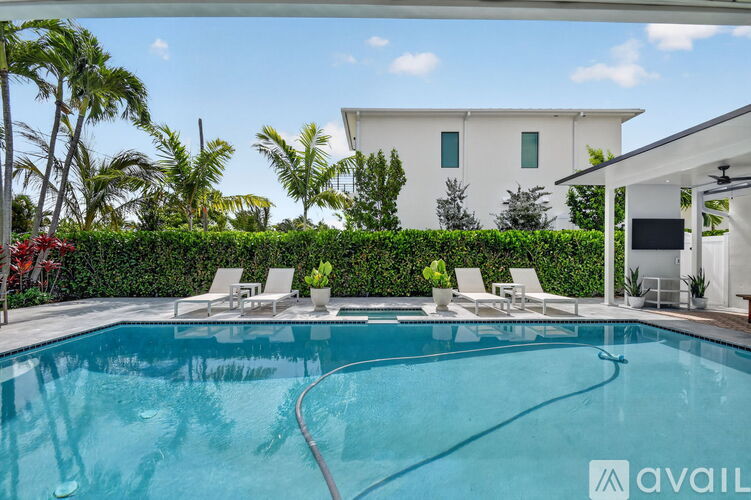 A swimming pool with a hedge and a white house in the background.