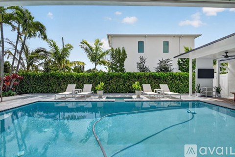 A swimming pool with a hedge and a white house in the background.