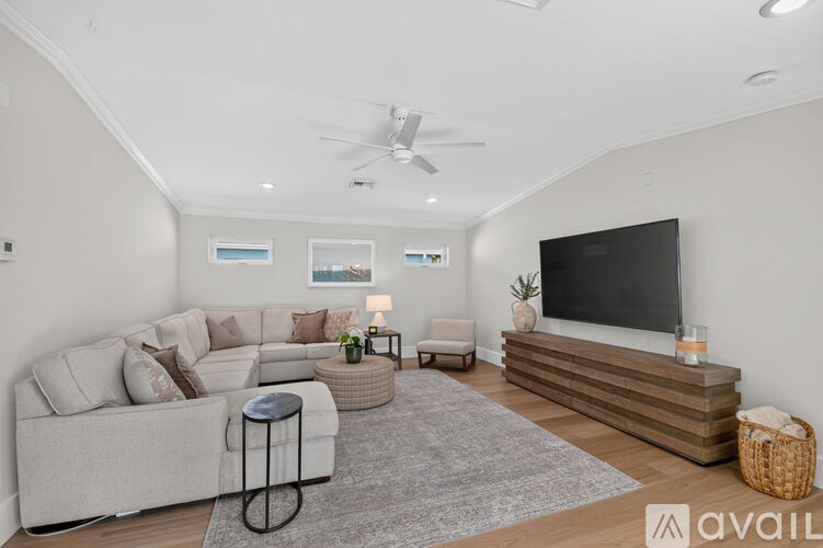 A living room with a grey sofa, a grey rug, a black TV and a wooden staircase.
