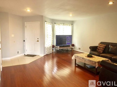 A living room with a black leather couch and a television.