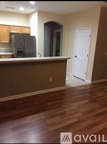 A kitchen with a refrigerator, cabinets, and a door.