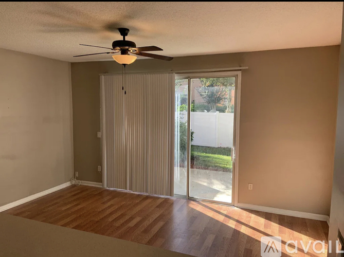 A room with a ceiling fan and sliding glass doors.