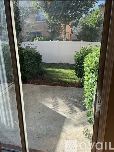 A patio with a white fence and green plants.