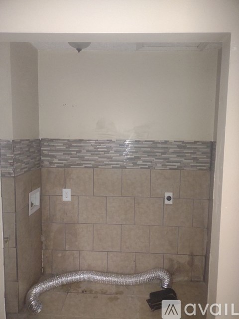 A bathroom with a shower and a silver hose.