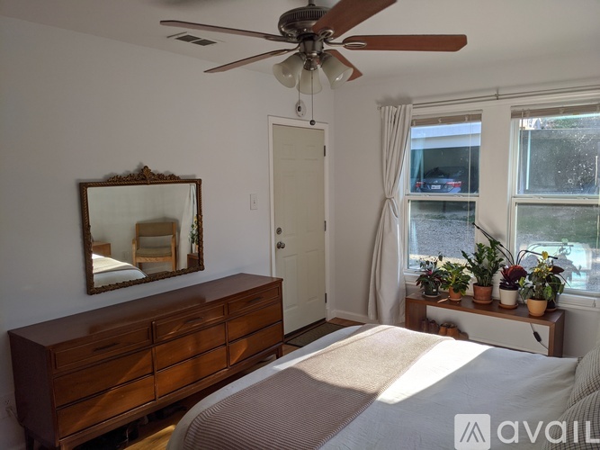 A bedroom with a bed, dresser, mirror, and window.