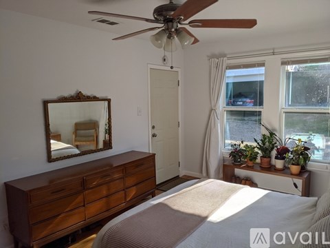 A bedroom with a bed, dresser, mirror, and window.
