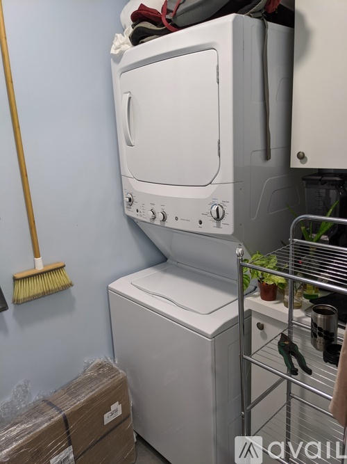 A white dishwasher is in a kitchen with a broom on the wall.
