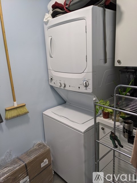 A white dishwasher is in a kitchen with a broom on the wall.