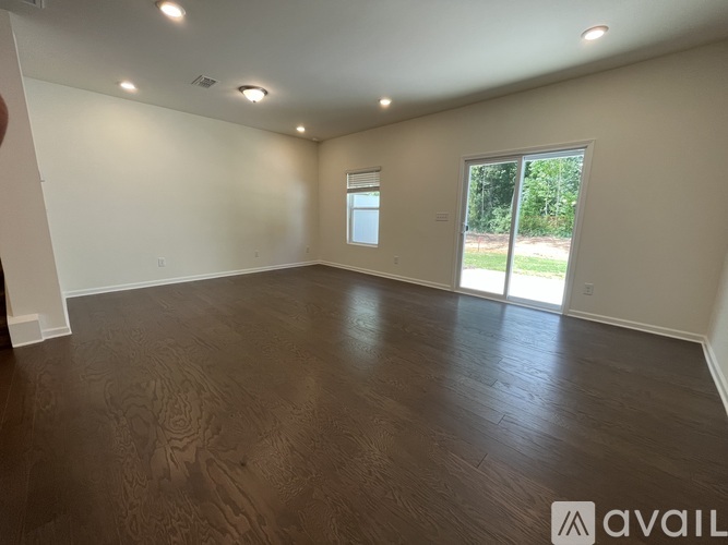 A spacious room with wooden flooring and a large window.