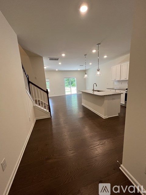 A spacious kitchen and living room with white cabinets and a dark hardwood floor.