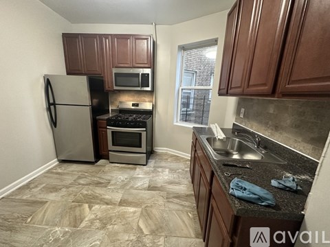 A kitchen with brown cabinets, a stove, a refrigerator, and a microwave.