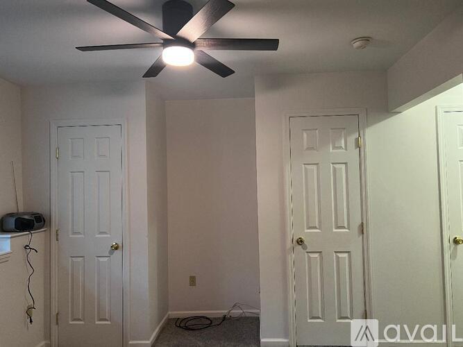 A room with a ceiling fan and three doors.