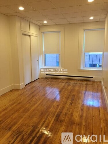 A room with wooden flooring and a window with blinds.