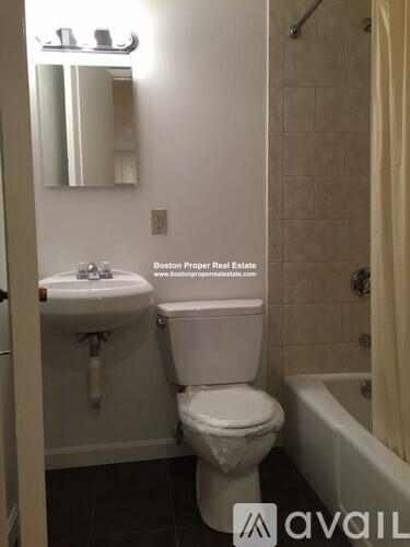 A white toilet in a bathroom with a white sink and a bathtub.