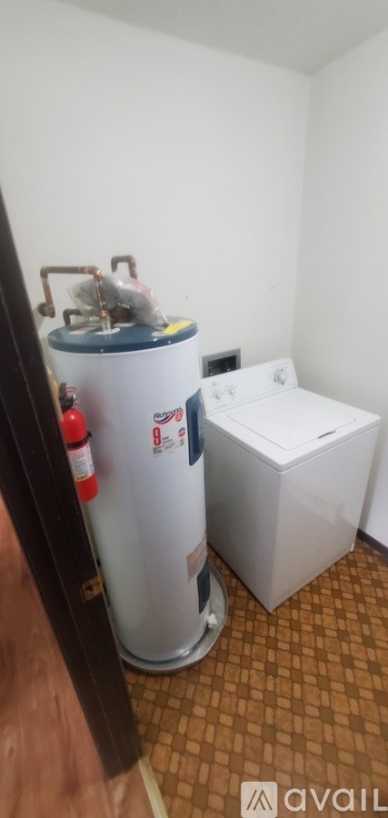 A white water heater with a red fire extinguisher next to it.