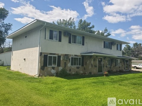 A house with a white exterior and a stone wall is available for rent.