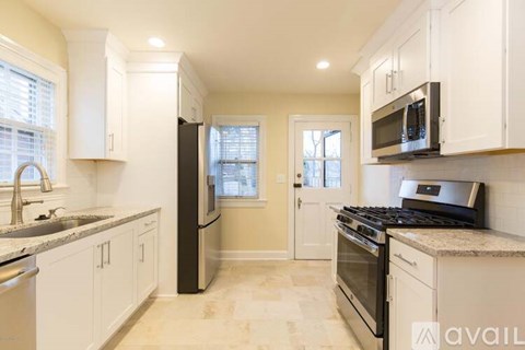 A kitchen with white cabinets and a black fridge.