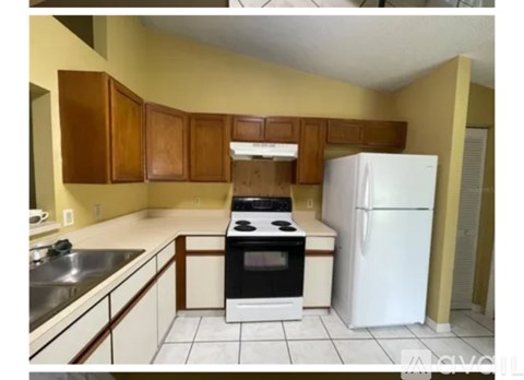 A kitchen with a white refrigerator, black stove, and white cabinets.