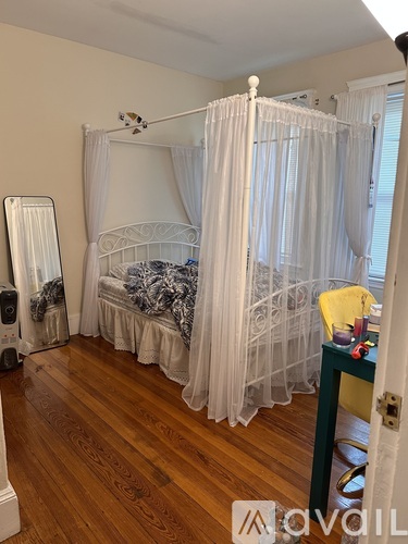 A bedroom with a bed covered in a white bedspread and a white canopy.