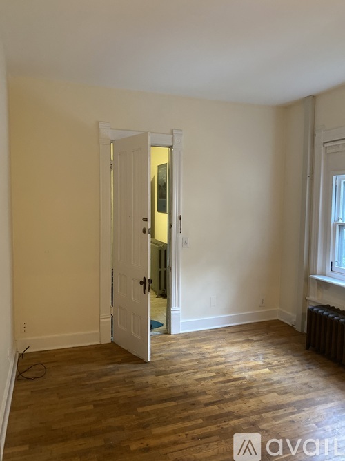 A room with a white door and wooden flooring.