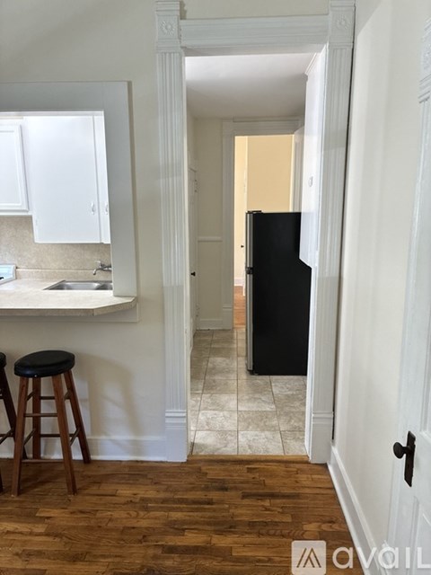 A kitchen with white cabinets and a black fridge.